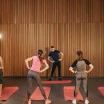 People stretching on yoga mats during a fitness class indoors.